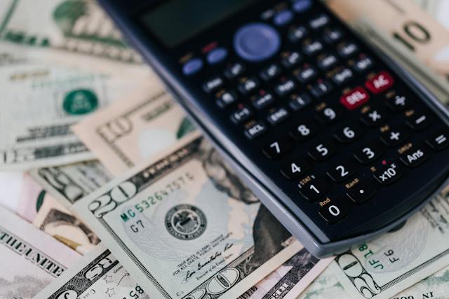 a-calculator-placed-on-top-of-scattered-us-dollar-bills a-calculator-placed-on-top-of-scattered-us-dollar-bills